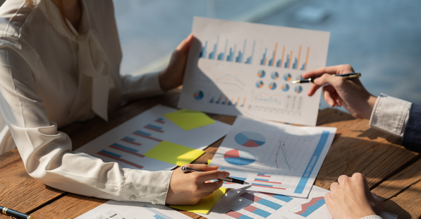 People outside collaborating at a table with documents of financial data