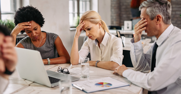 Stock image of people at a table looking stressed