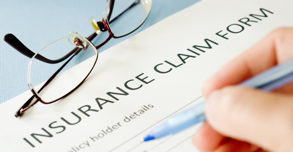 Image of an insurance claim document being filled in, a pair of glasses sits on top