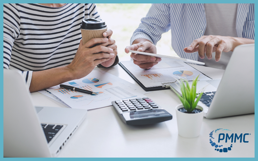 people sitting at a table with papers and laptops collaborating over strategic objectives