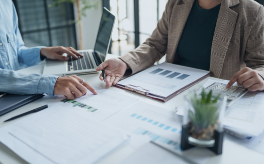 Twp people collaborating at a desk with data and contracts