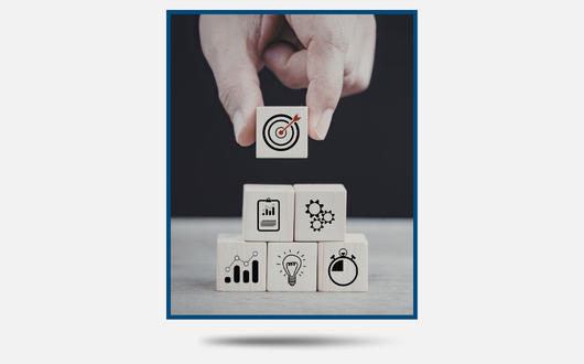 Stock image of a person placing a block with a bullseye over other blocks with various productivity symbols