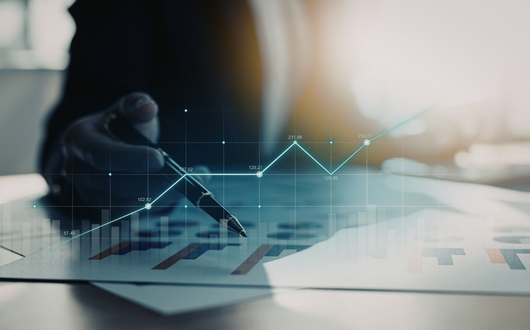 digital line graph floating in front of a person working on a report