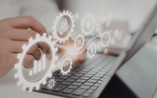 Digital gears with productivity icons floating above a laptop keyboard