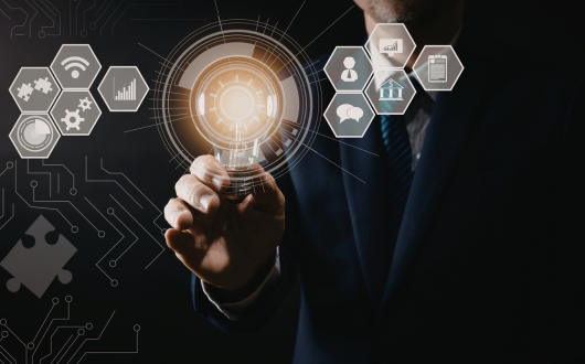 Image of a digital light bulb symbol surrounded by other technology symbols floating around it