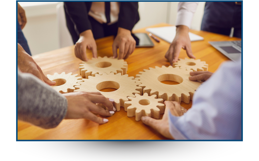 Image of people fitting wooden gears together on a table
